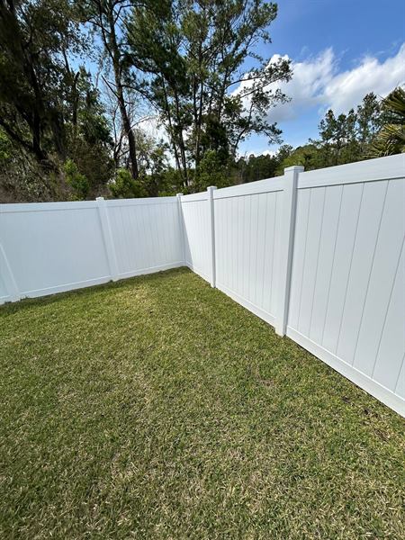 A white vinyl privacy fence in the same backyard after cleaning