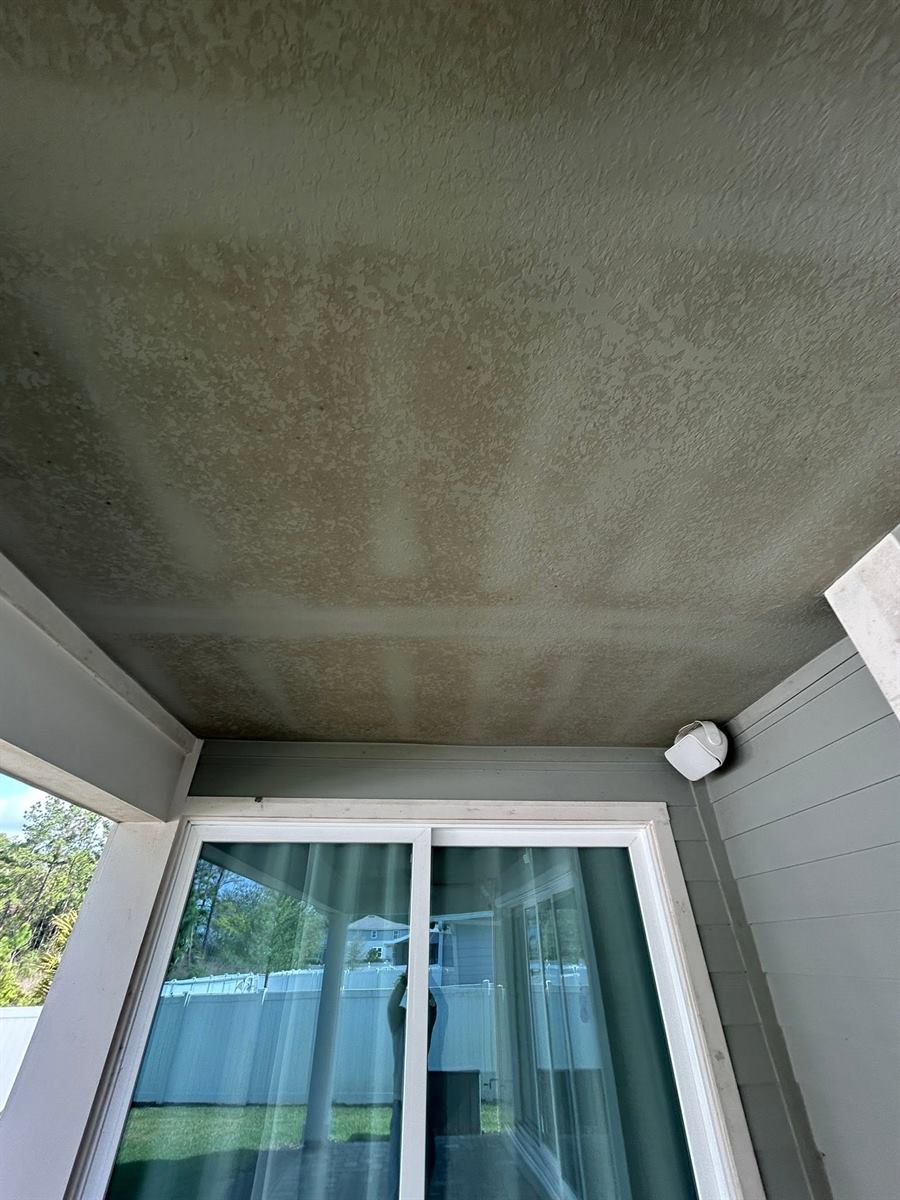 Lanai ceiling before cleaning: blotchy mildew and dirt across the stucco
