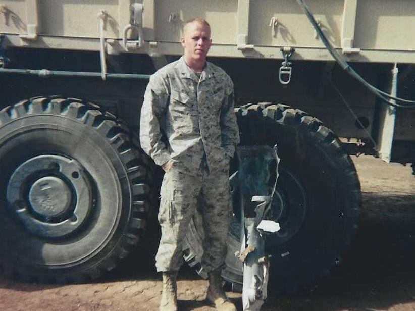 Ian in uniform during his military service, standing in front of a military truck
