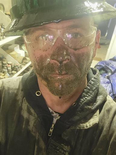 Ian after a long day on the job, face and safety glasses covered in grime