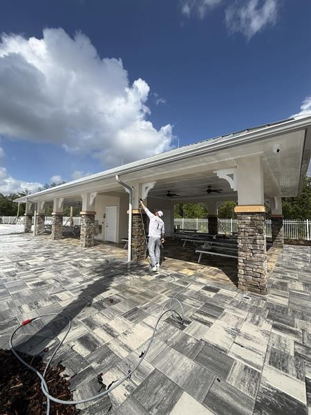 Pressure washing the paver patio of a large covered pavilion
