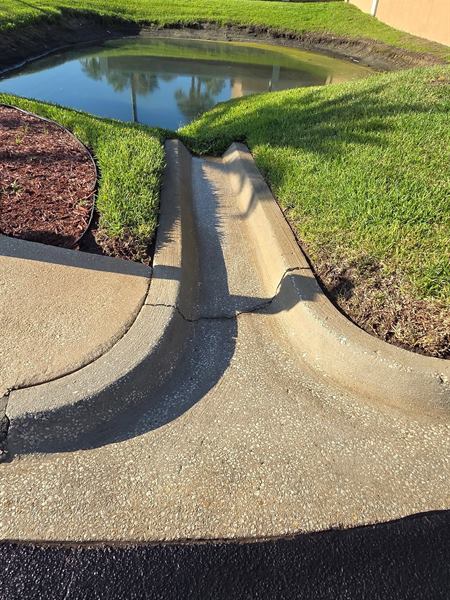 Concrete drainage curb by a retention pond after cleaning