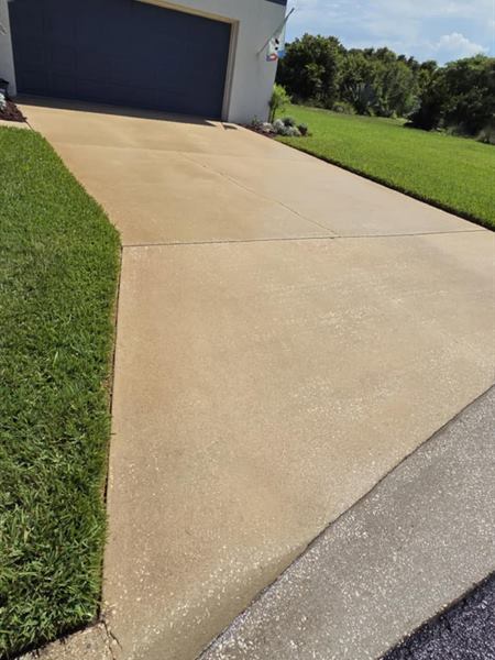 Clean concrete driveway edge next to the lawn, after pressure washing