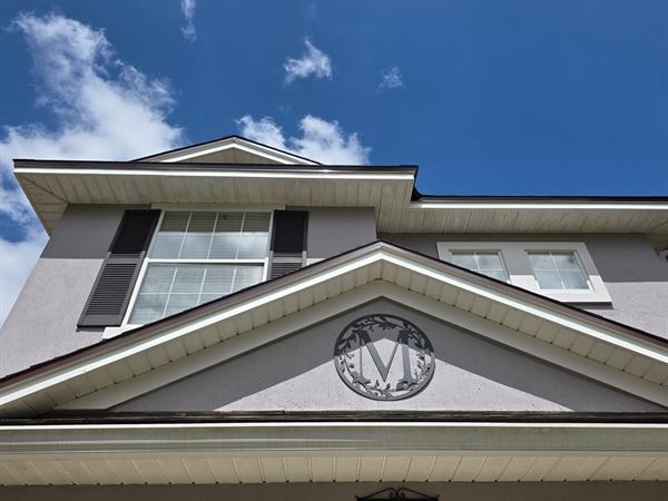 Gable and monogram trim on a grey stucco house after an exterior wash
