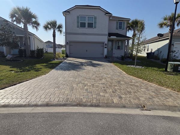 Paver driveway leading to a two-story home, seen from the street, after cleaning