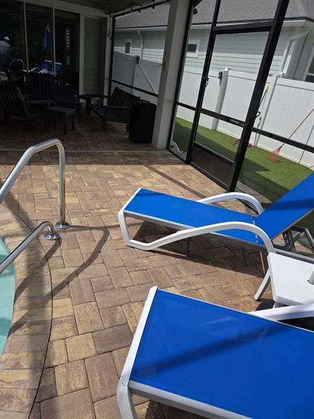 Clean paver pool deck with blue lounge chairs