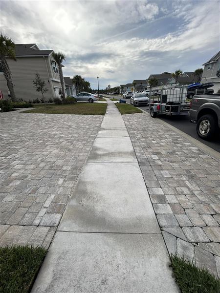 The same sidewalk from further down the street, with a visible line between the washed and unwashed sections