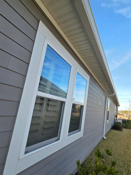 Clean grey siding and white window trim along the side of a house