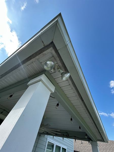 Clean white porch column and soffit after cleaning, under a blue sky